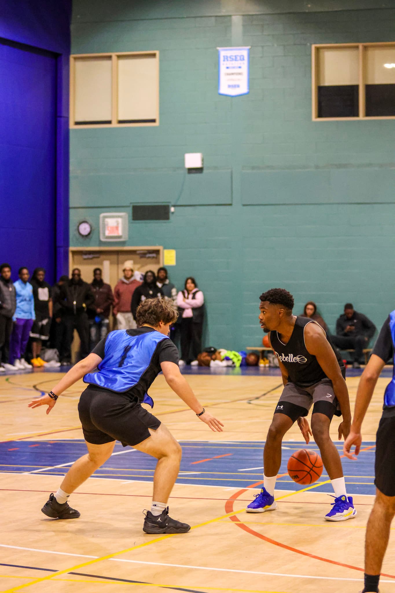 Un joueur dribble face à son défenseur pendant un match de basketball de la LCM
