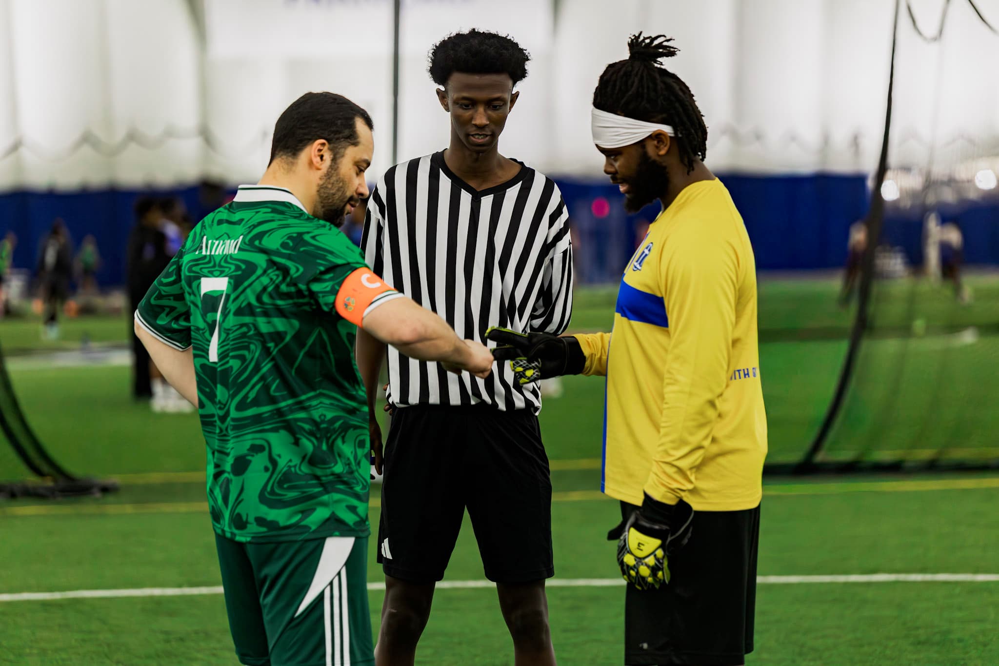 Un capitaine et le gardien adverse se saluent devant l’arbitre avant un match de soccer