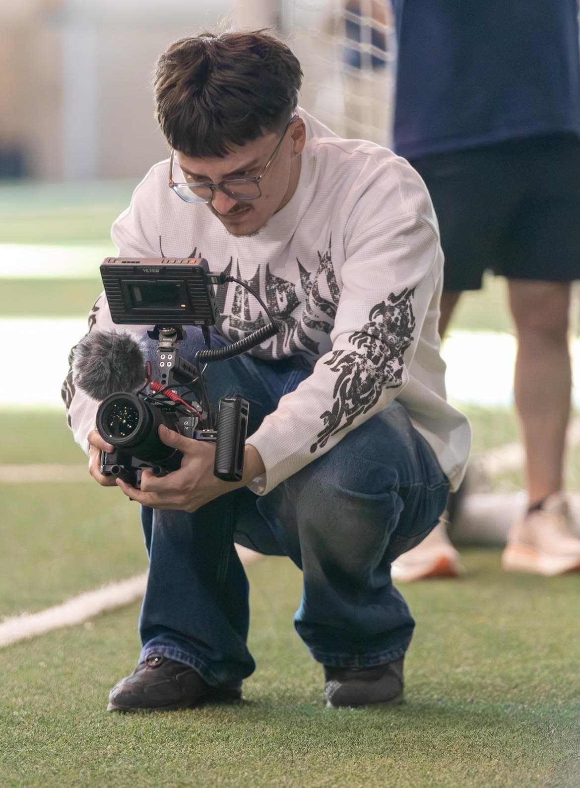 Vidéographe accroupi qui filme un match de la ligue